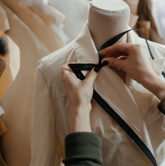 person in white dress shirt and black necktie holding white suit jacket